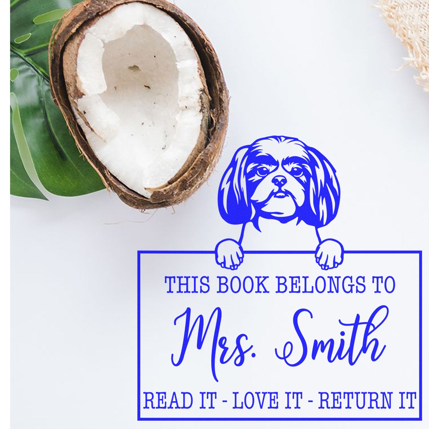 Blue custom book stamp seal with dog graphic, reading This Book Belongs to Mrs. Smith, beside a coconut.