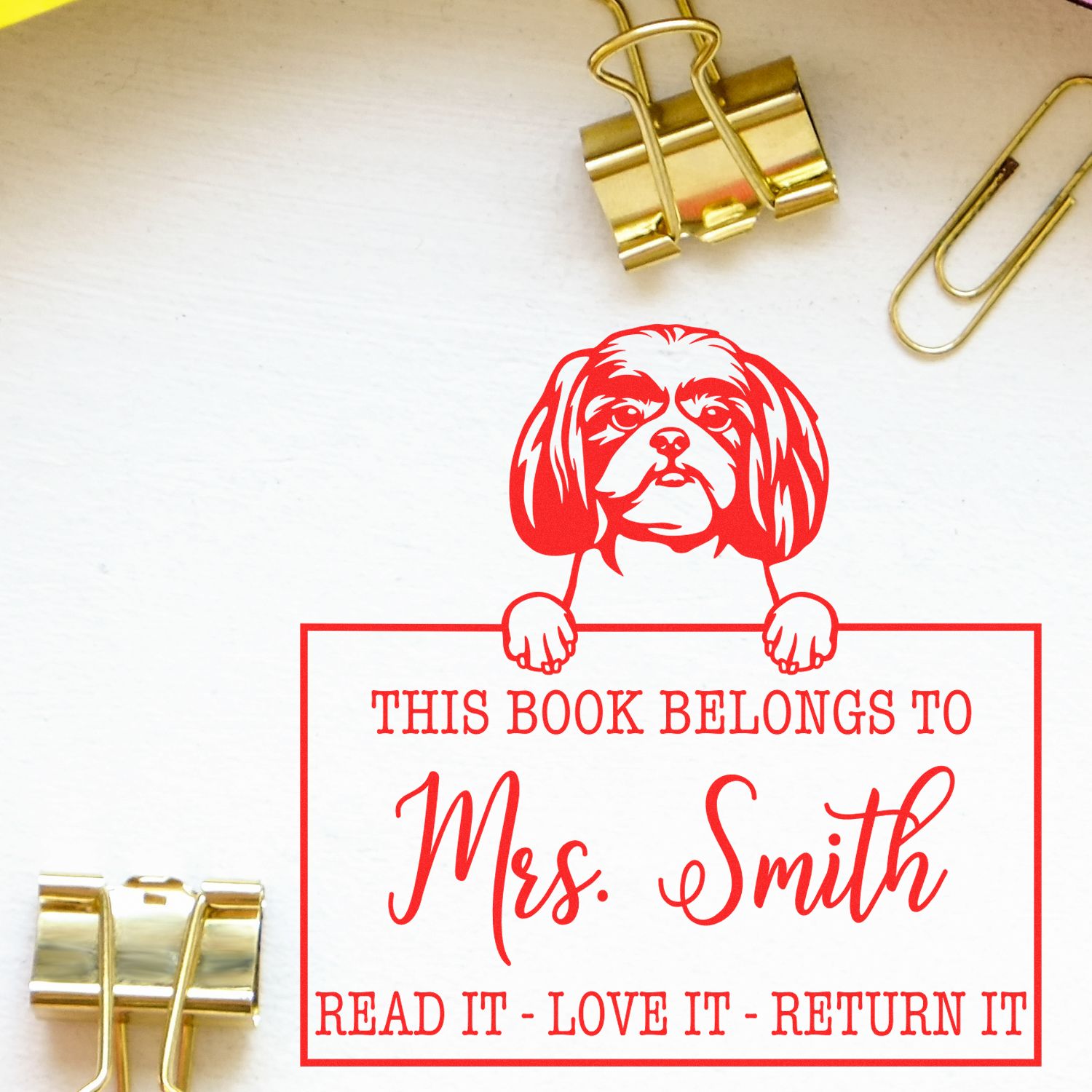 Red custom book stamp and seal with dog design, This Book Belongs to Mrs. Smith, on white paper with gold binder clips.