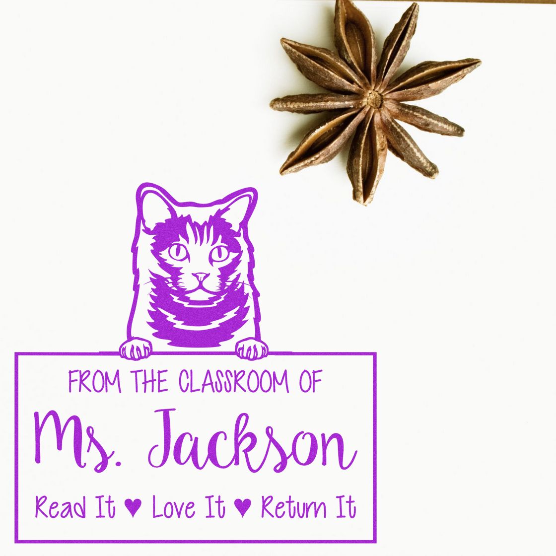 Purple cat classroom stamp reading Ms. Jackson, Read It Love It Return It with brown star-shaped seal accent on white background.
