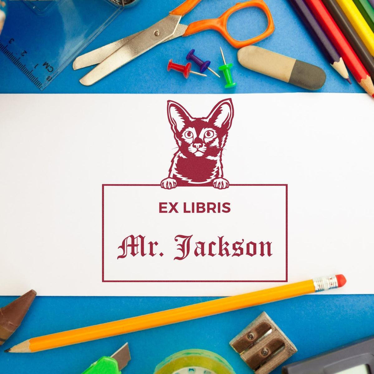 Custom ex libris stamp and seal with burgundy cat and Mr. Jackson on white paper, surrounded by blue stationery.