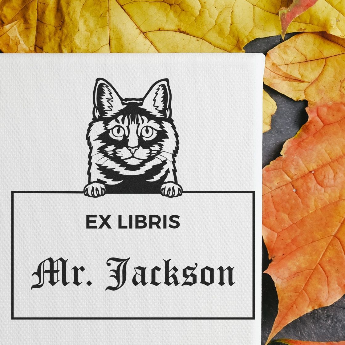 Black-and-white cat ex libris bookplate stamp and seal with Mr. Jackson text on white paper, on autumn leaves.