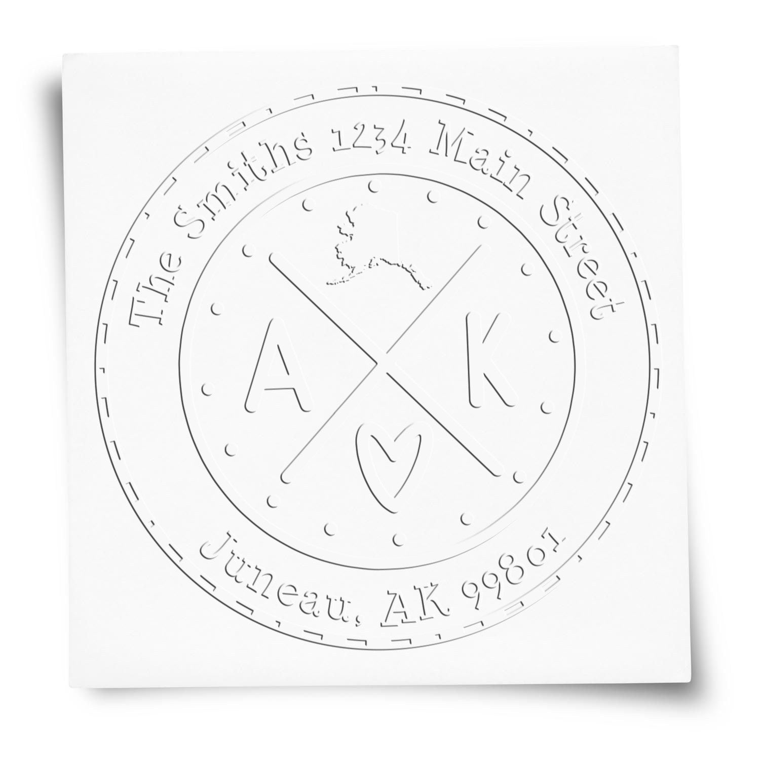 White embossed custom address seal stamp with circular monogram, initials A K, and heart detail.