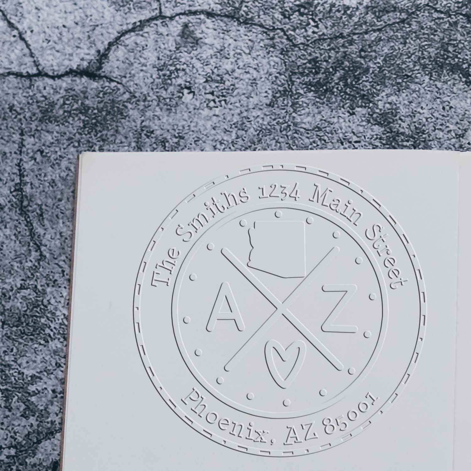 White embossed custom stamp and seal with circular AZ logo and The Smiths address on a gray textured surface