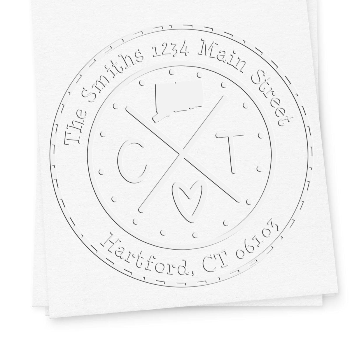 White embossed custom stamp seal with circular monogram, heart icon, and address text on paper.