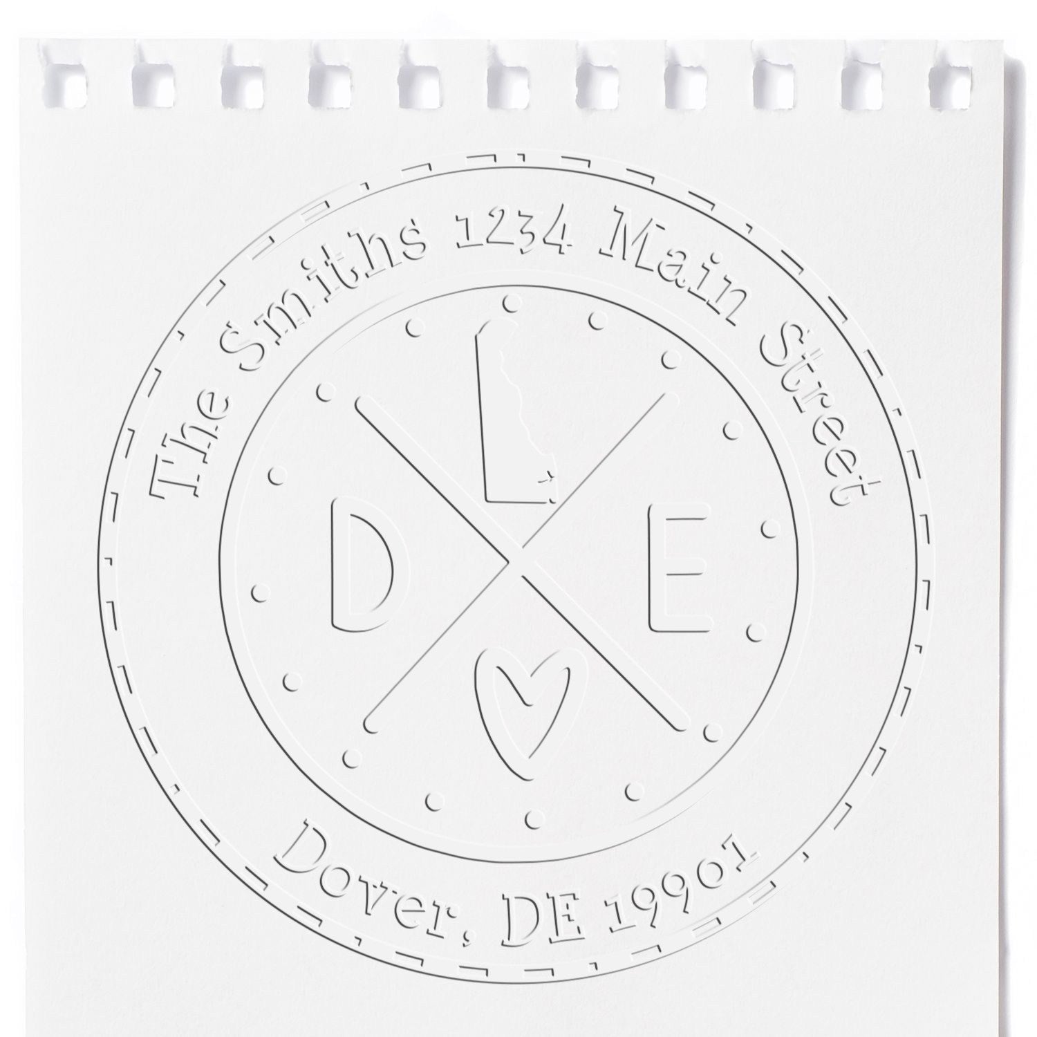 White embossed round address stamp seal with D and E monogram, heart, and text: The Smiths, 1234 Main Street, Dover, DE 19901.