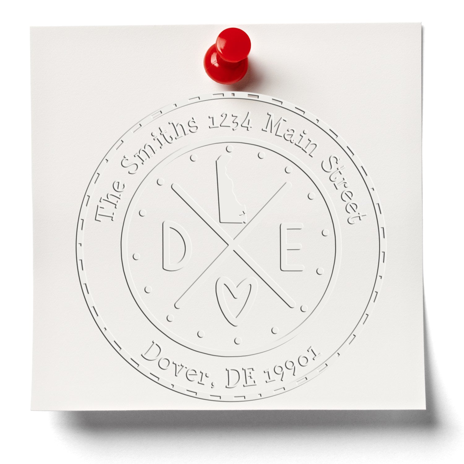White embossed custom seal stamp on white paper, pinned with a red tack; circular design for The Smiths, Dover DE 19901