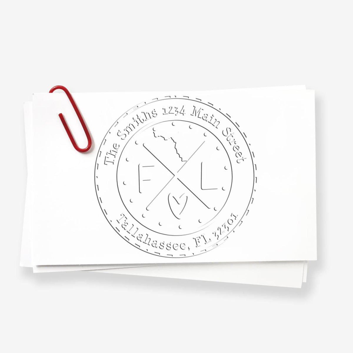 White paper stack with circular embossed seal stamp, gray line-art logo, and a red paperclip.