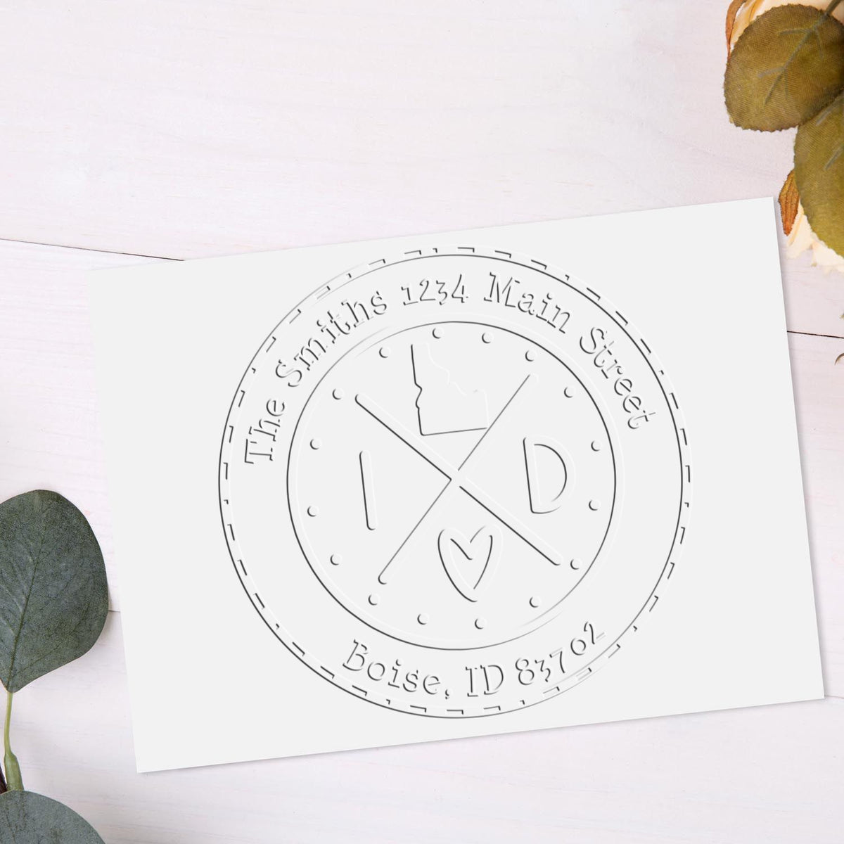 White custom stamp seal with embossed circular logo, gray lettering, crossed lines, and Boise, ID address.