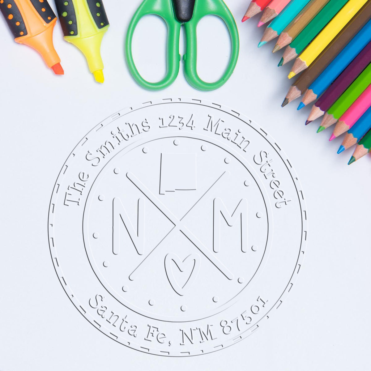 White embossing stamp seal for The Smiths address, framed by green scissors, orange highlighters, and colorful pencils.