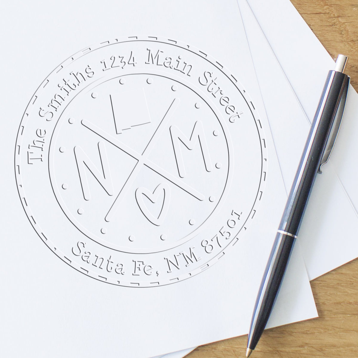Custom embossing seal for The Smiths, with circular address text, on white paper beside a silver pen.