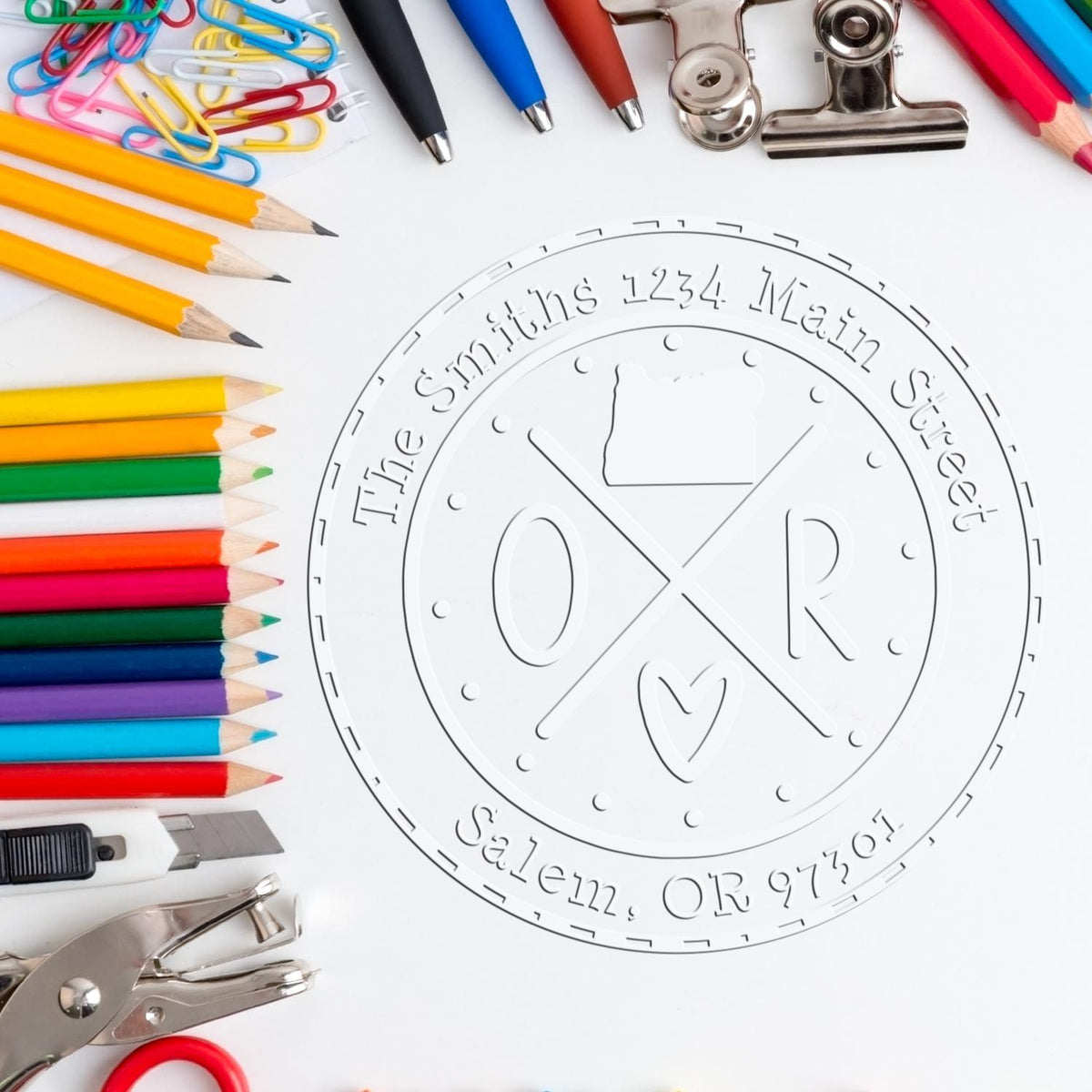 Custom embossed seal stamp for The Smiths, surrounded by colorful pencils, pens, paper clips, and metal office tools.