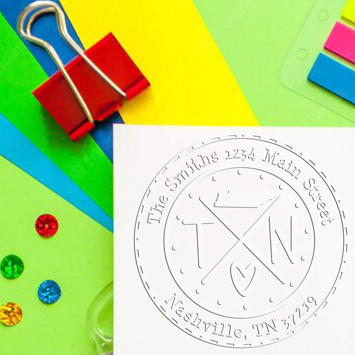 Colorful stationery with red binder clip and embossed custom seal stamp on white paper, plus blue, green, yellow and pink tabs.