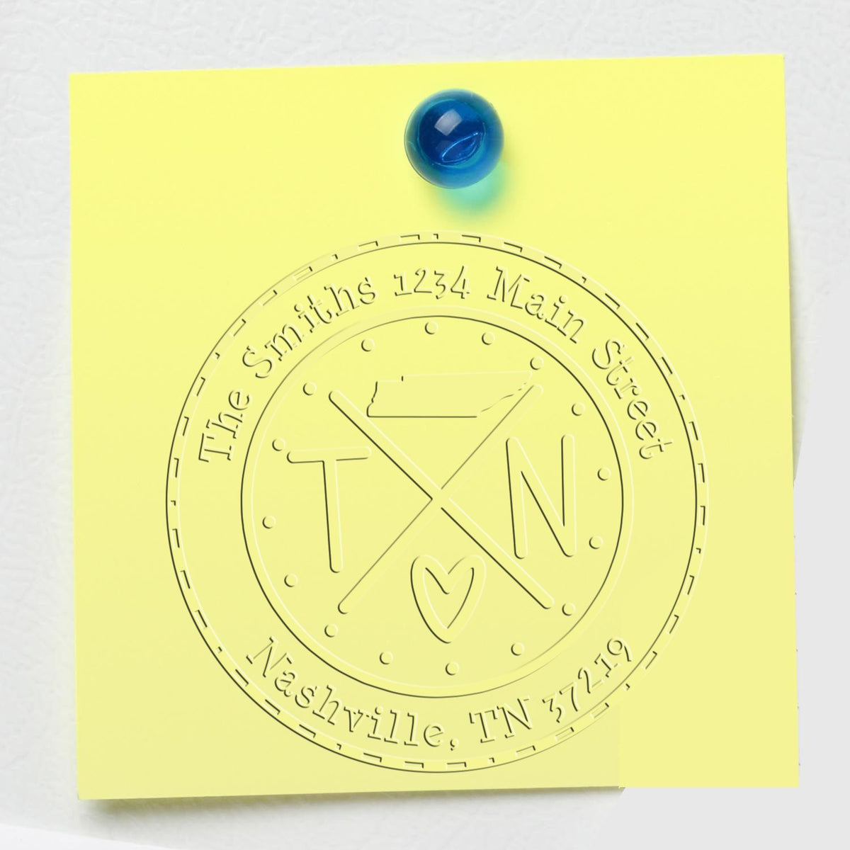Yellow sticky note with blue tack and embossed custom address seal stamp reading The Smiths, Nashville TN.