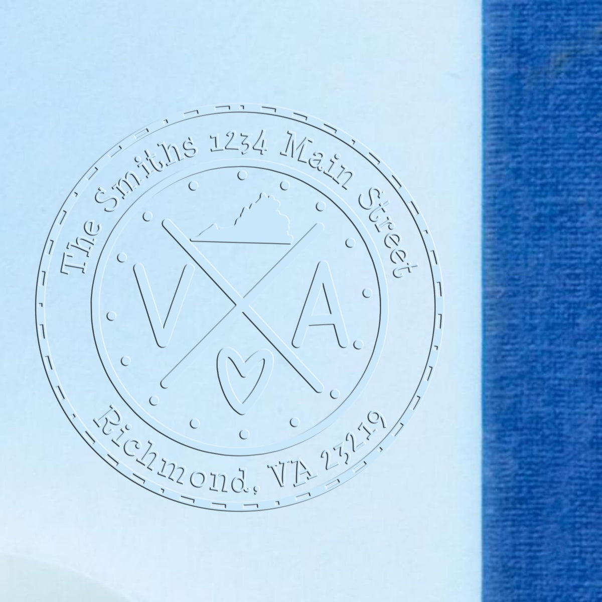 Embossed silver circular stamp seal reading The Smiths, 1234 Main Street, Richmond, VA 23219 on pale blue paper.