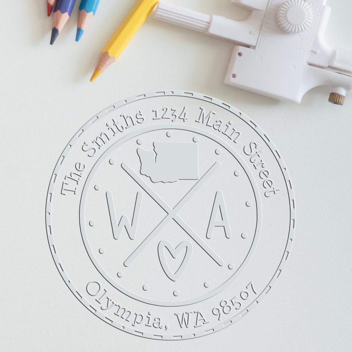 White embossed round custom seal stamp with WA, Olympia address, and colored pencils on a white background.
