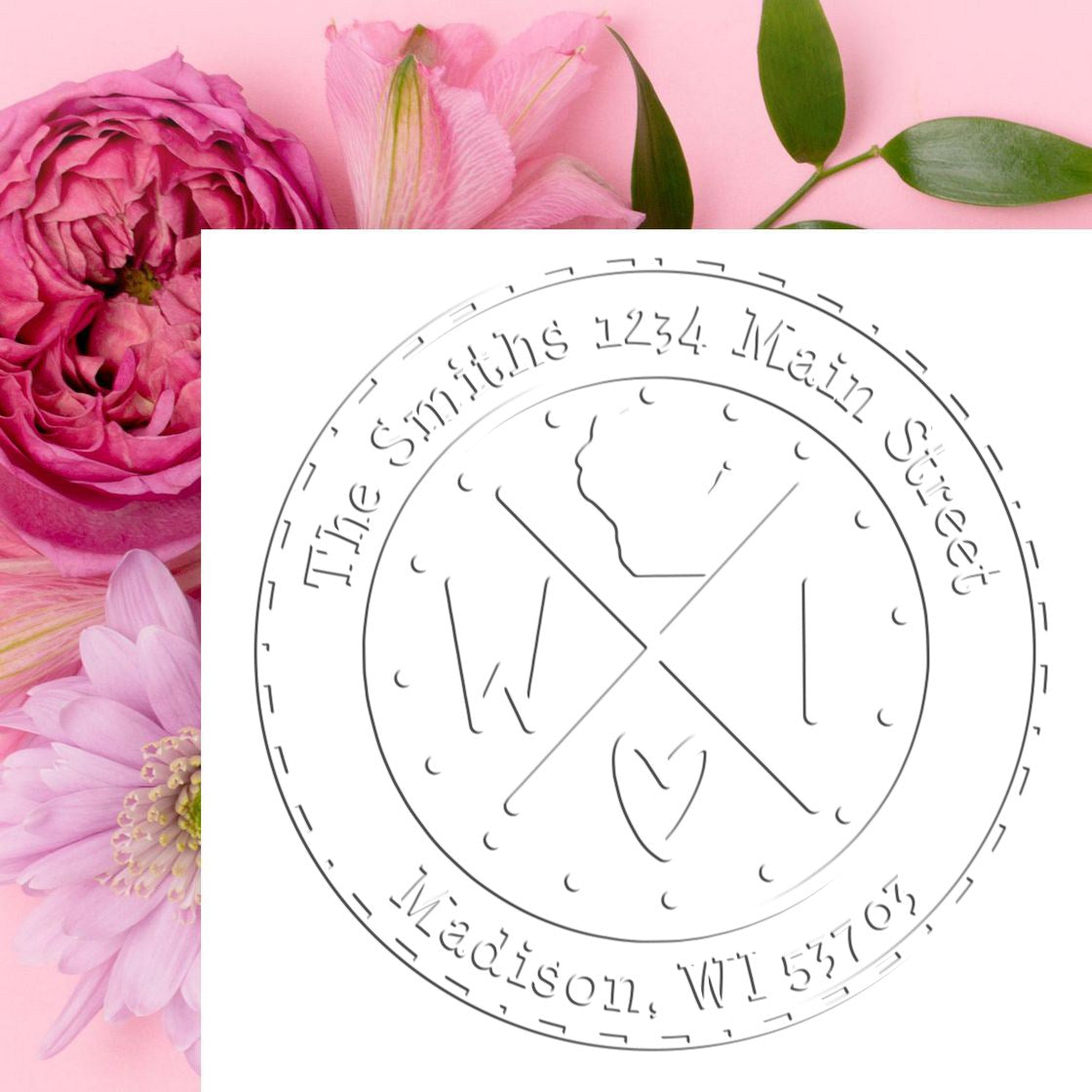Circular gray custom return address stamp and seal on a soft pink floral background with pink blossoms and green leaves.