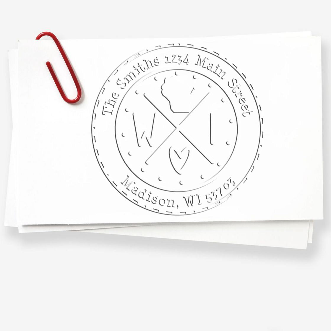 Embossed circular seal stamp on white paper with a red paperclip, gray lettering, and crossed initials.