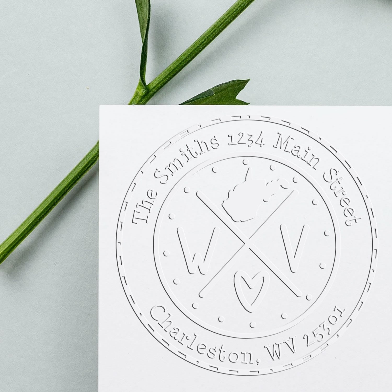Embossed white circular address stamp seal with green plant stems on a pale gray background.