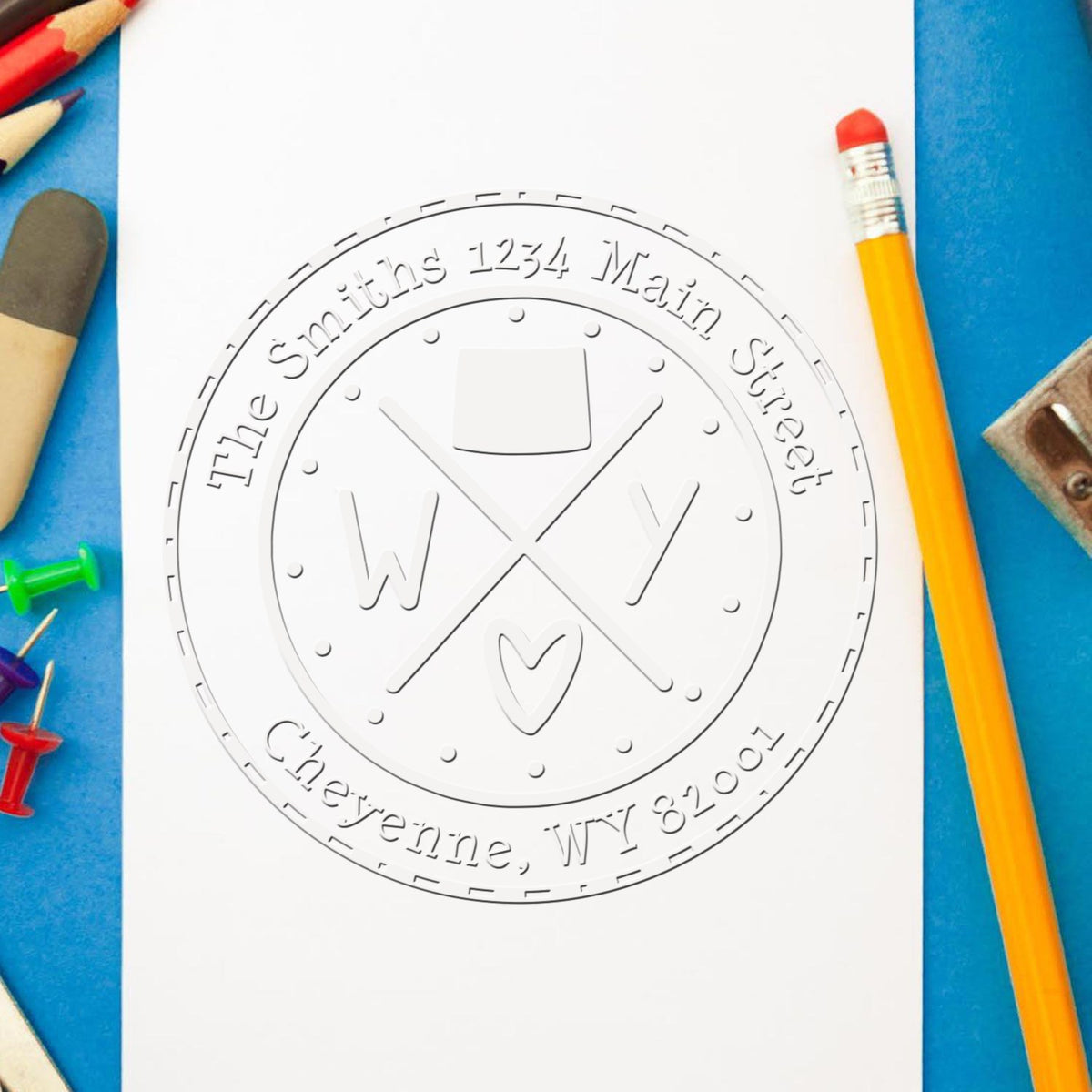 Embossed circular stamp seal on white paper, with Smiths address text, surrounded by pencils on a blue background.