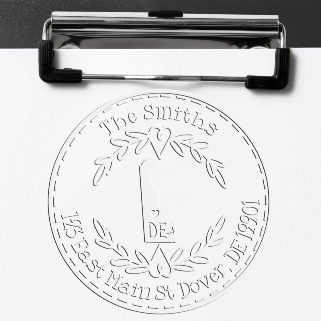 Black clipboard holding white paper with embossed circular seal stamp for The Smiths, with leaves and key emblem.