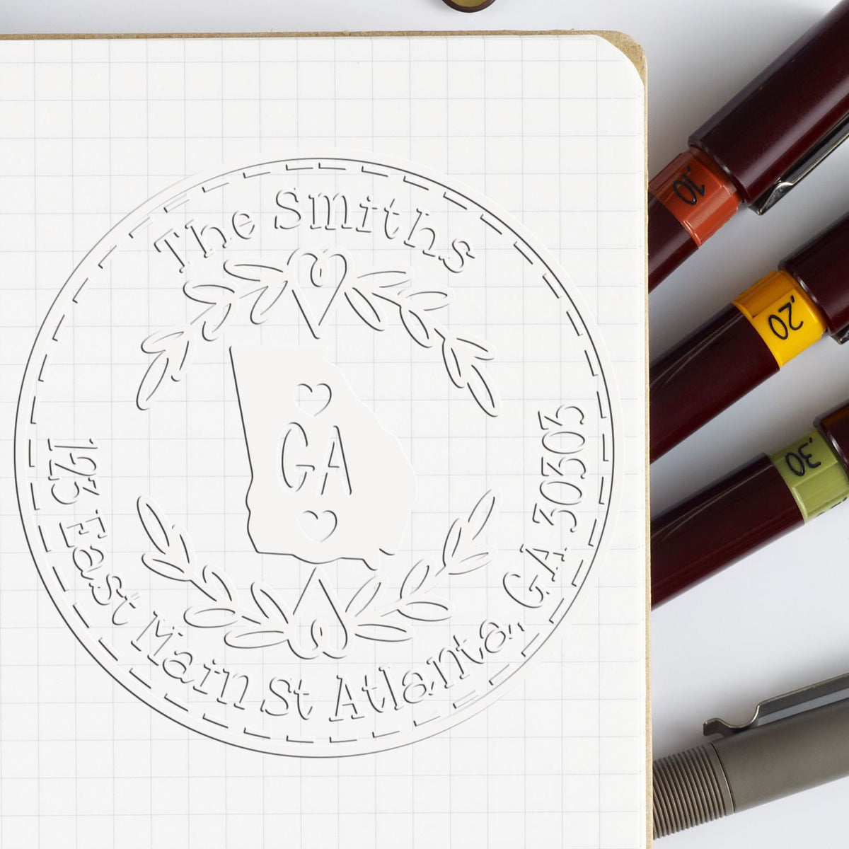 Custom round stamp and seal design with Georgia outline, The Smiths, laurel wreath, and numbered markers on graph paper.