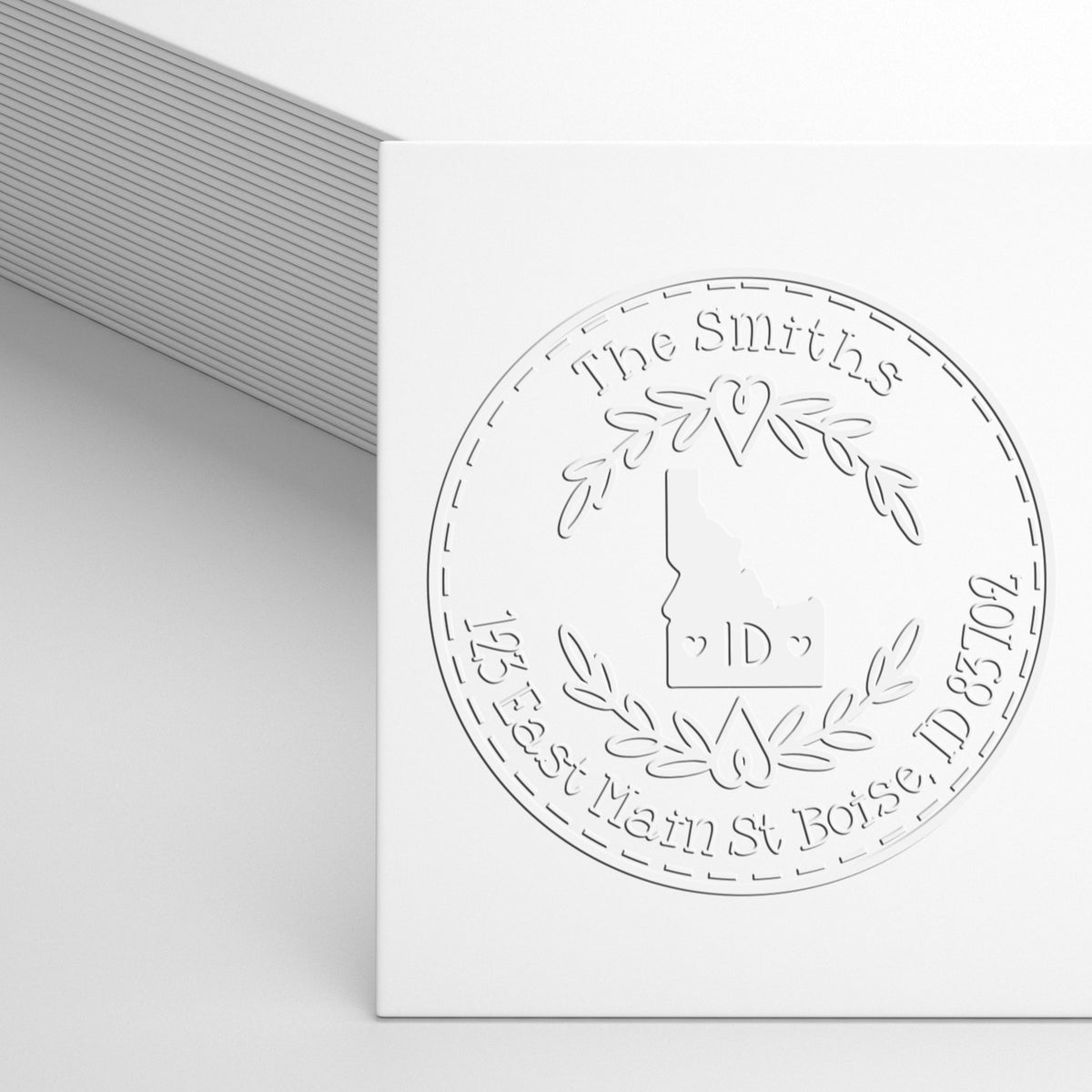 White embossed custom stamp seal featuring a wreath, heart, and Louisiana outline on a white card.