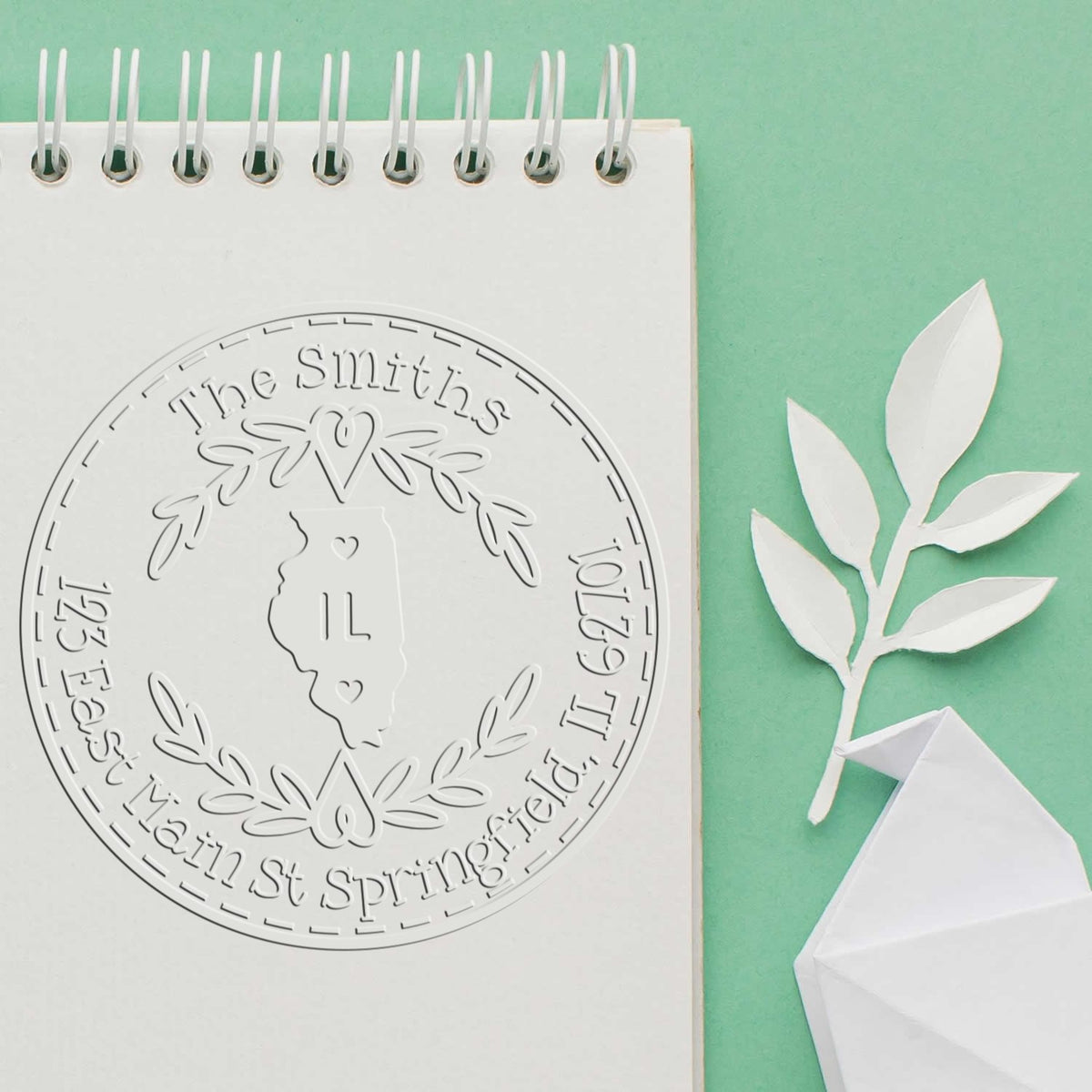 Trodat State Love Stamps Illinois custom return address embosser seal in use, featuring Illinois state outline and intricate embossed design.