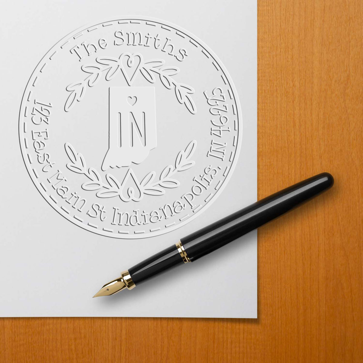 Embossed white custom seal for The Smiths with Indiana icon, beside a black fountain pen on white paper over a wood desk.