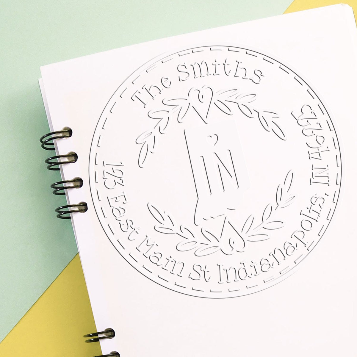 White circular embossing seal with laurel wreath and The Smiths text on pastel green and yellow paper.