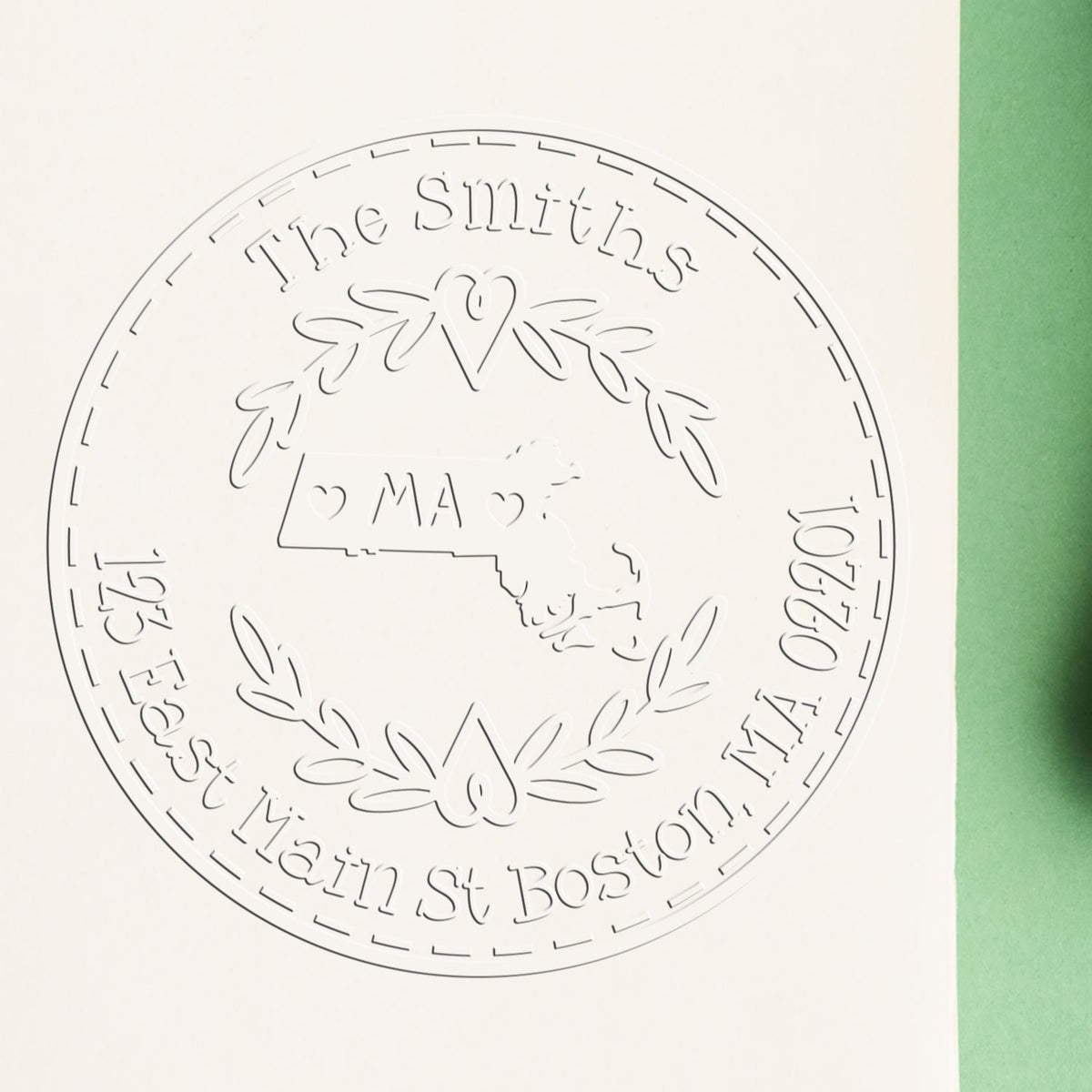 Embossed circular family seal stamp for The Smiths, with laurel wreath, hearts, and Massachusetts map on white paper with green edge.