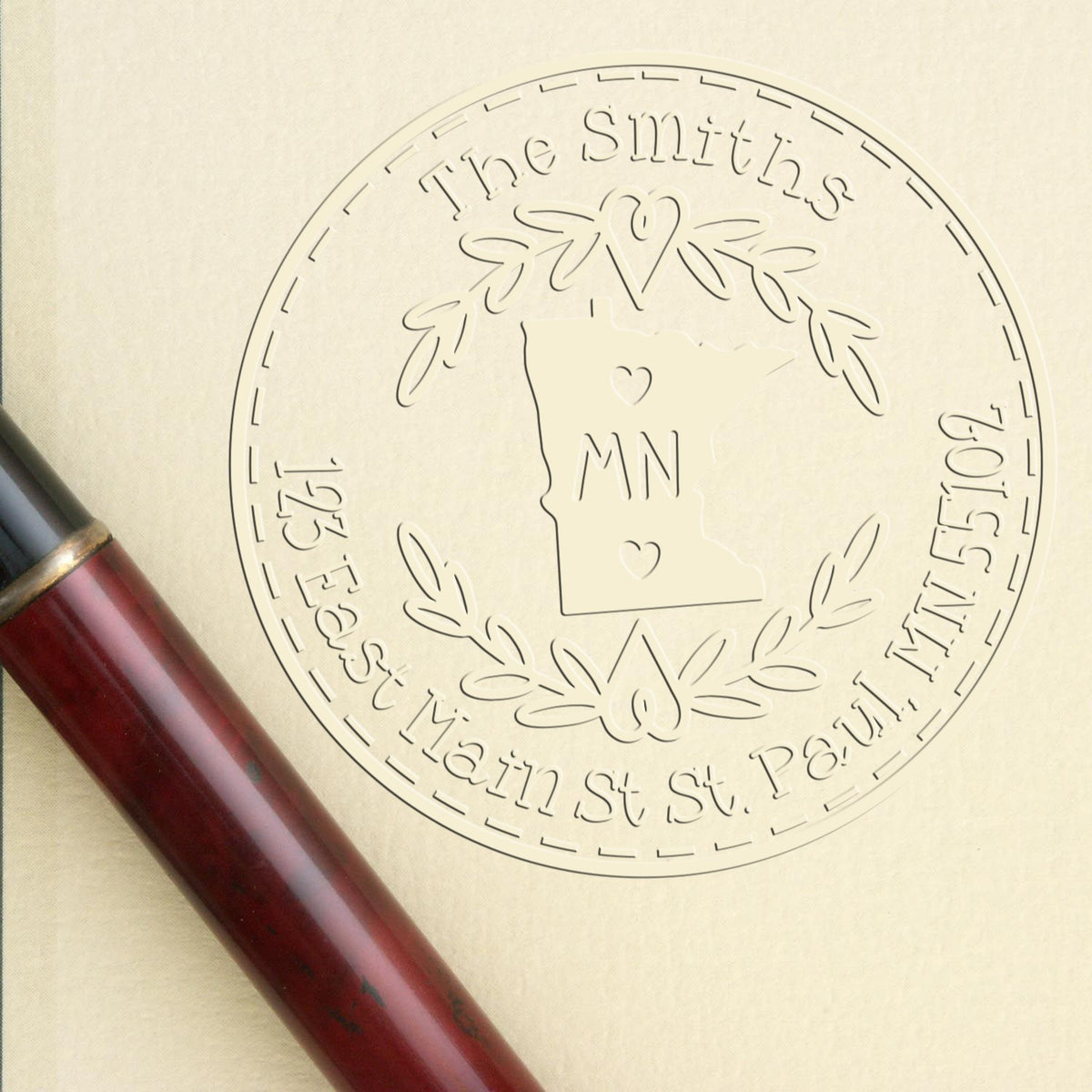 Custom round embosser seal with Minnesota outline, The Smiths, and dark red wooden stamp handle on cream paper.