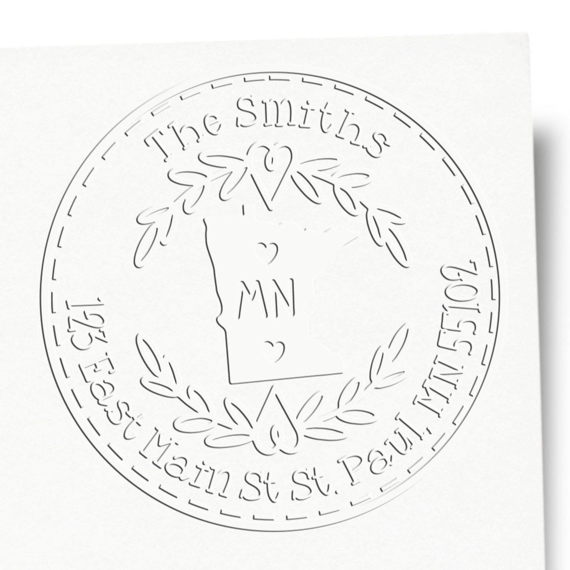 White embossing stamp seal with The Smiths, MN monogram, floral wreath, and state outline in raised gray.