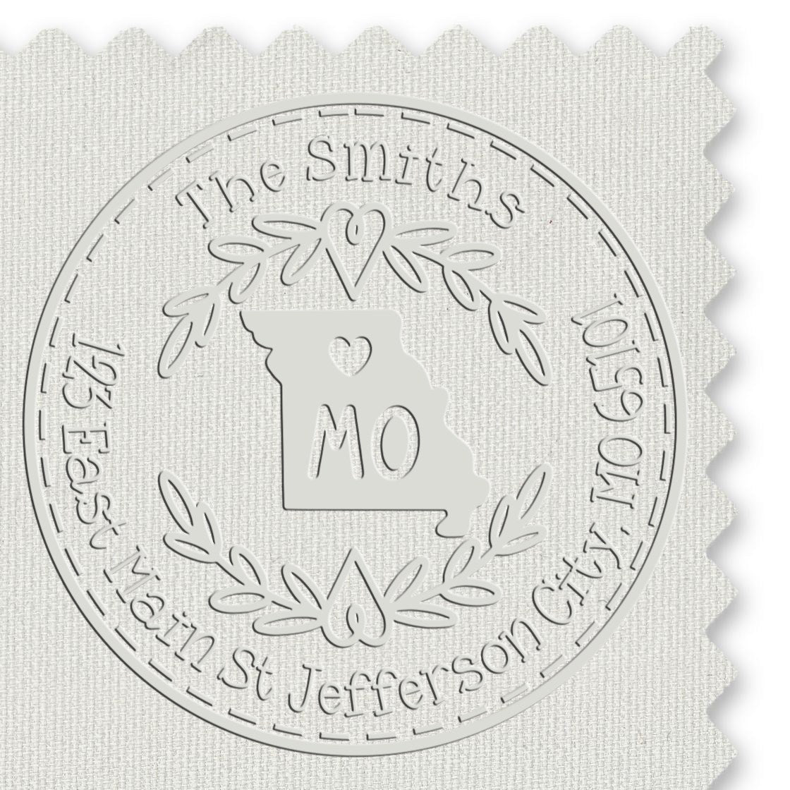 White embossed custom stamp seal with Missouri outline, MO, and laurel wreath on textured fabric.