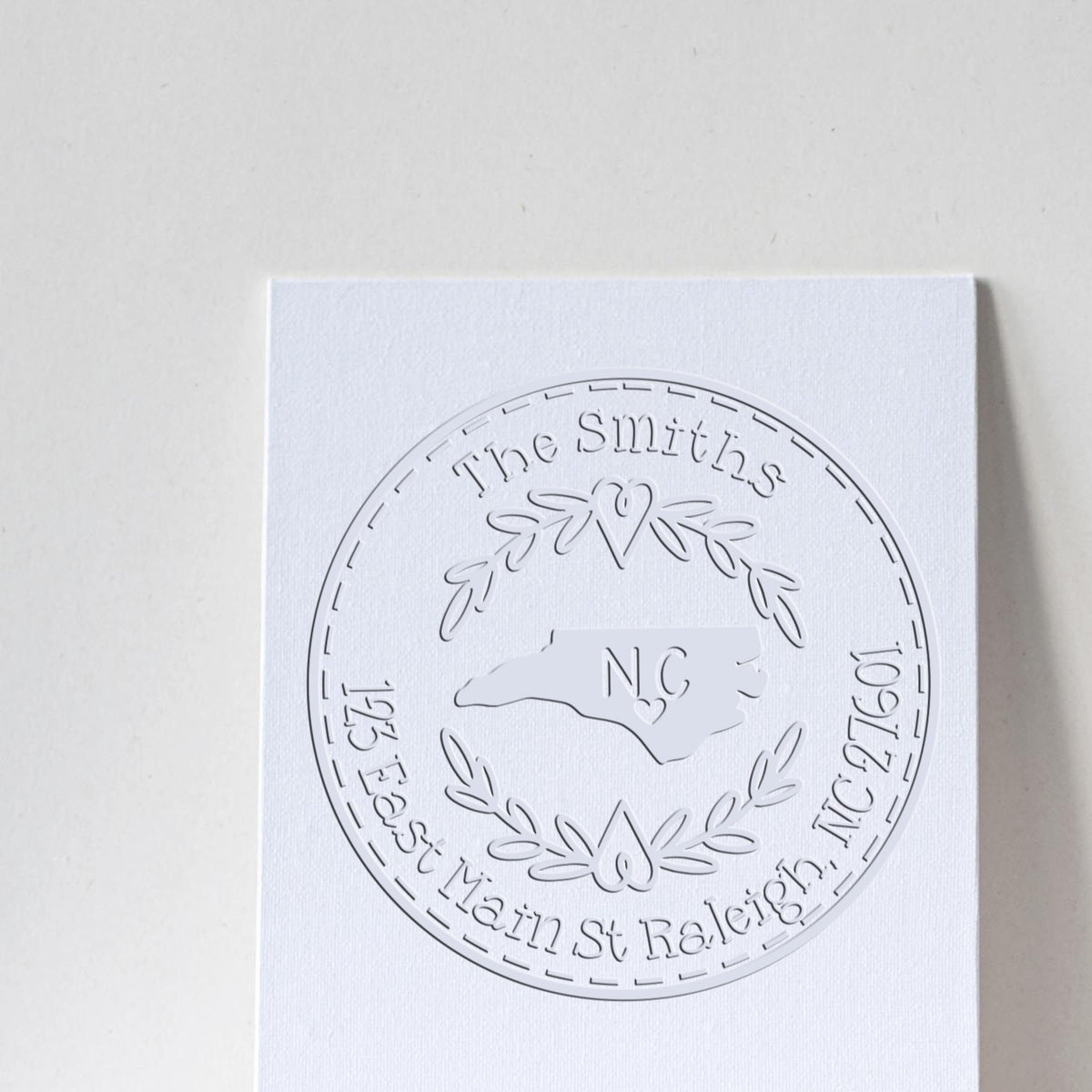Trodat State Love Stamps NC custom mail address embossed seal with state-shaped design in use on a letter.