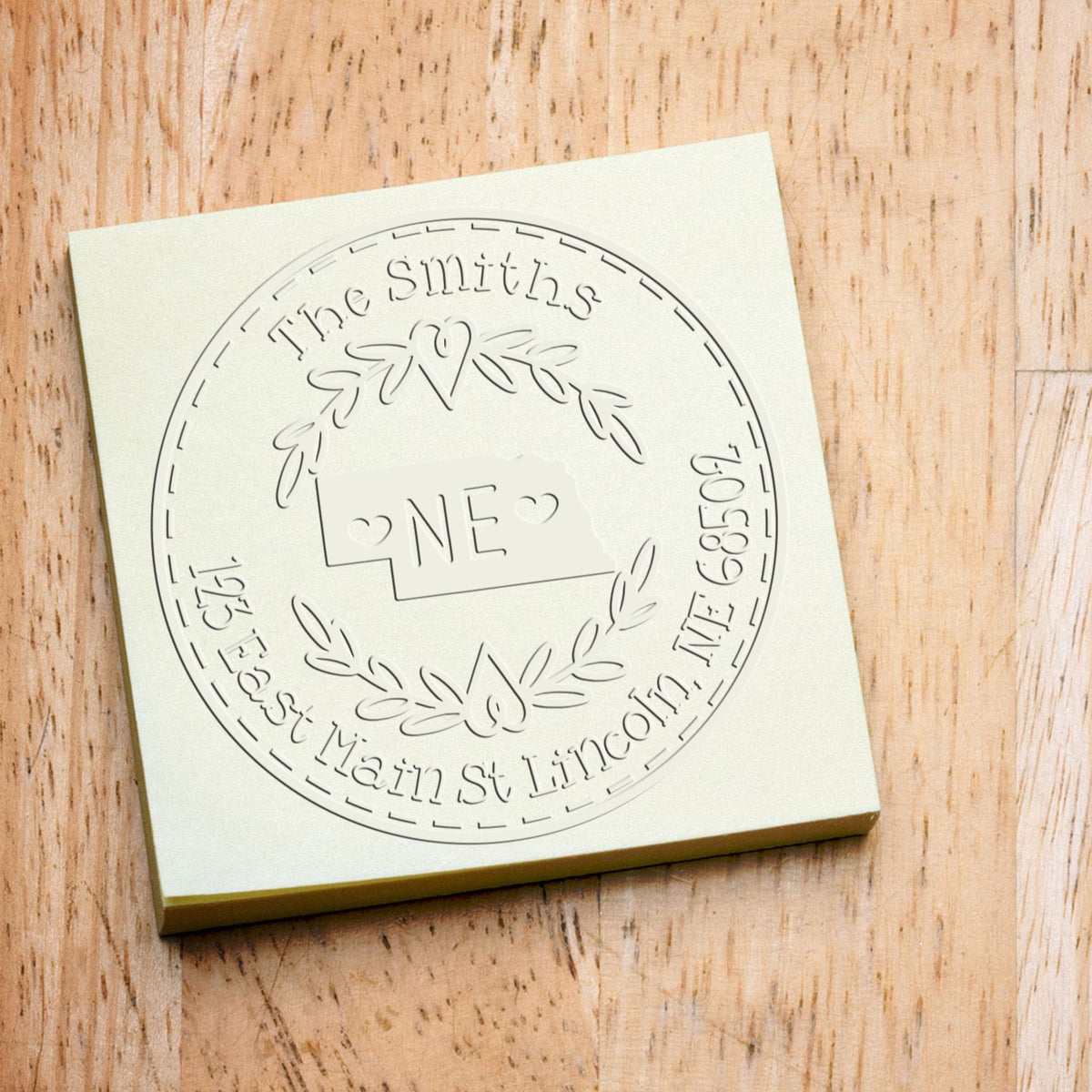 Cream custom stamp and seal block with embossed circular logo, laurel wreath, hearts, and The Smiths on a wood background.