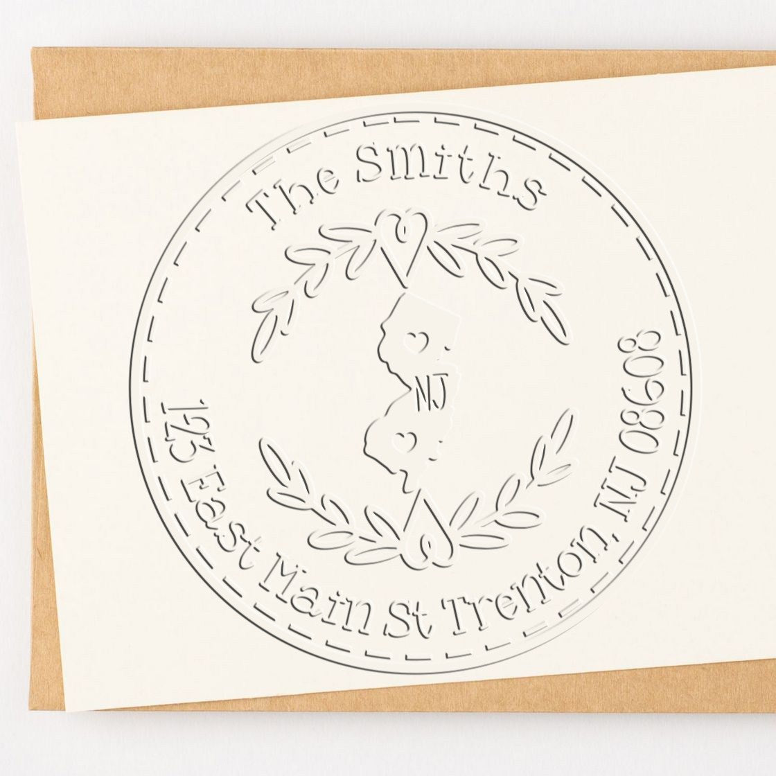 Embossed round stamp and seal in white on cream cardstock, with laurel wreath and family-name text.