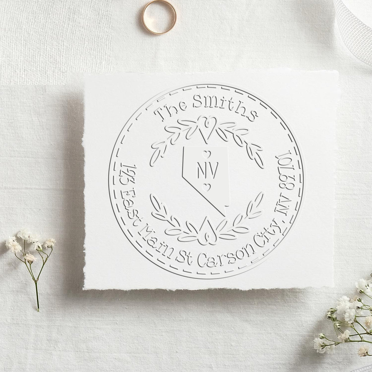 White custom embossing stamp and seal with circular wreath, monogram NV, and The Smiths wedding details on textured paper.