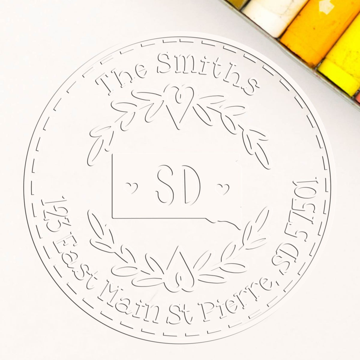 Trodat State Love Stamps SD custom name and address embosser seal with a state-shaped embossing in use on paper.