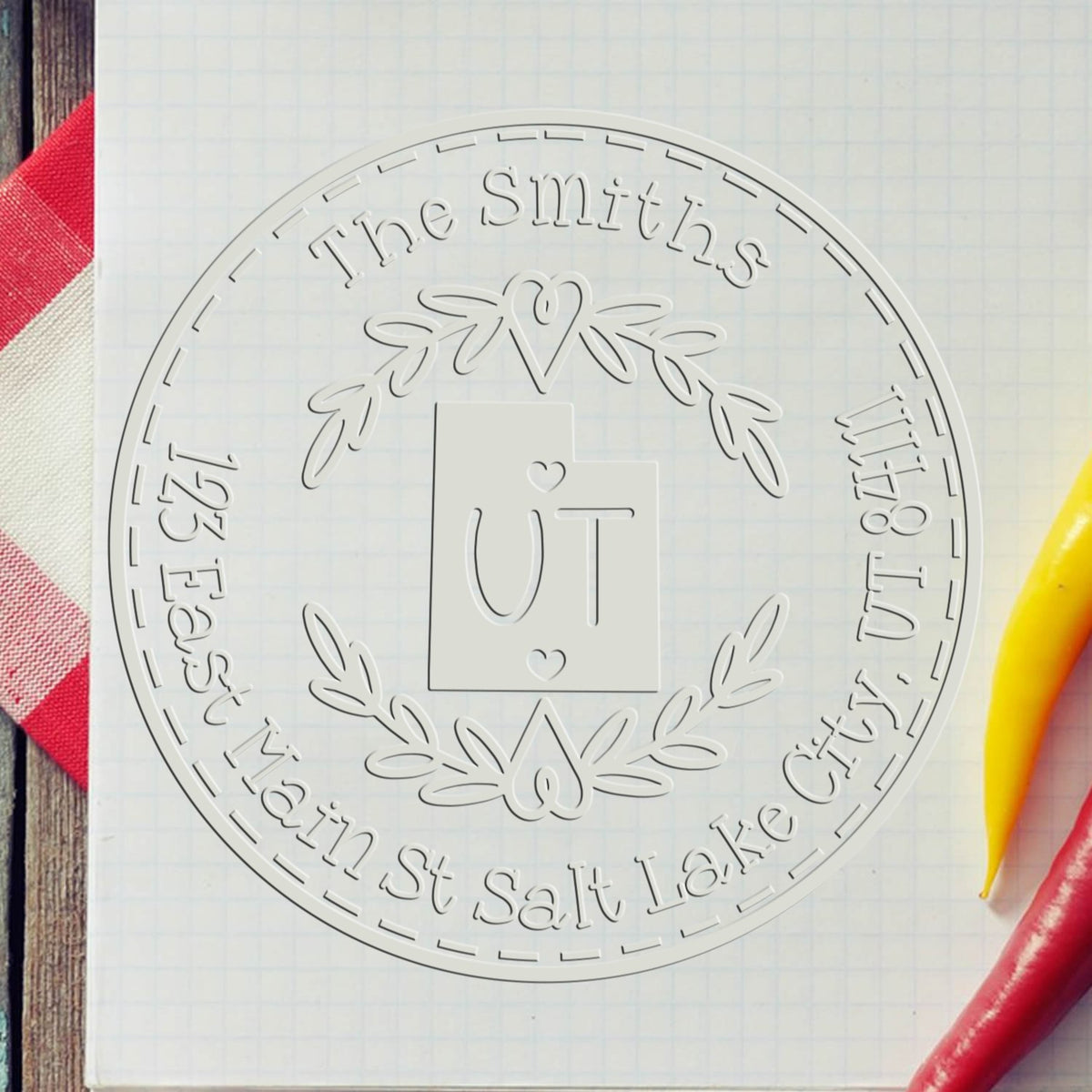 Clear round embossing seal for The Smiths, with heart wreath logo and Salt Lake City address on white grid paper.