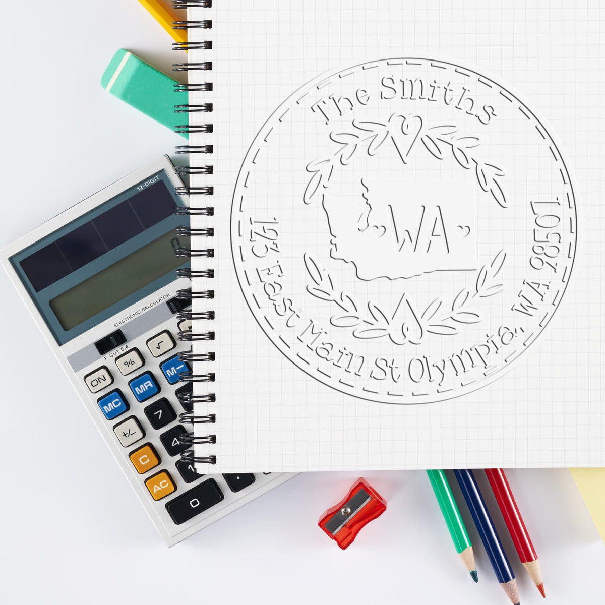 Embossed circular Washington state seal for The Smiths on graph notebook, beside calculator, pencils, eraser, and sharpener.