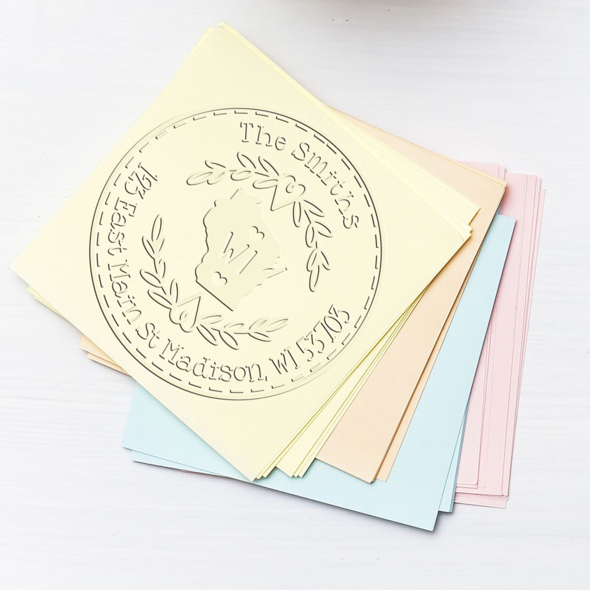 Custom stamp and seal sample sheets with embossed circular crest design in cream, blue, pink, and beige.