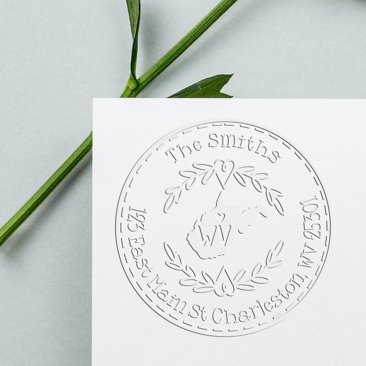 Embossed white circular stamp seal on white card, with green stem on pale gray background and The Smiths text.