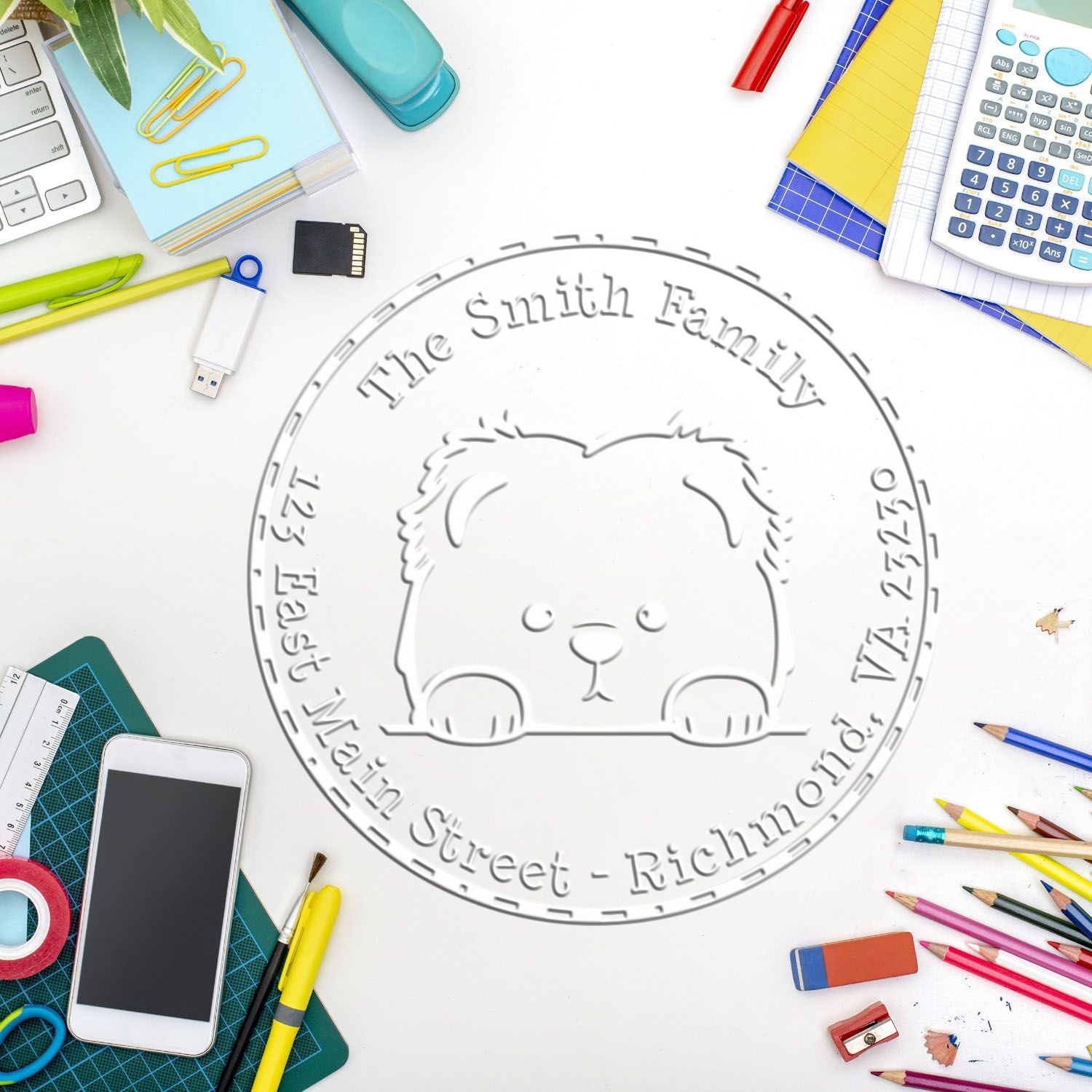Custom gray family stamp seal with bear emblem on white desk, surrounded by colorful stationery and office supplies.