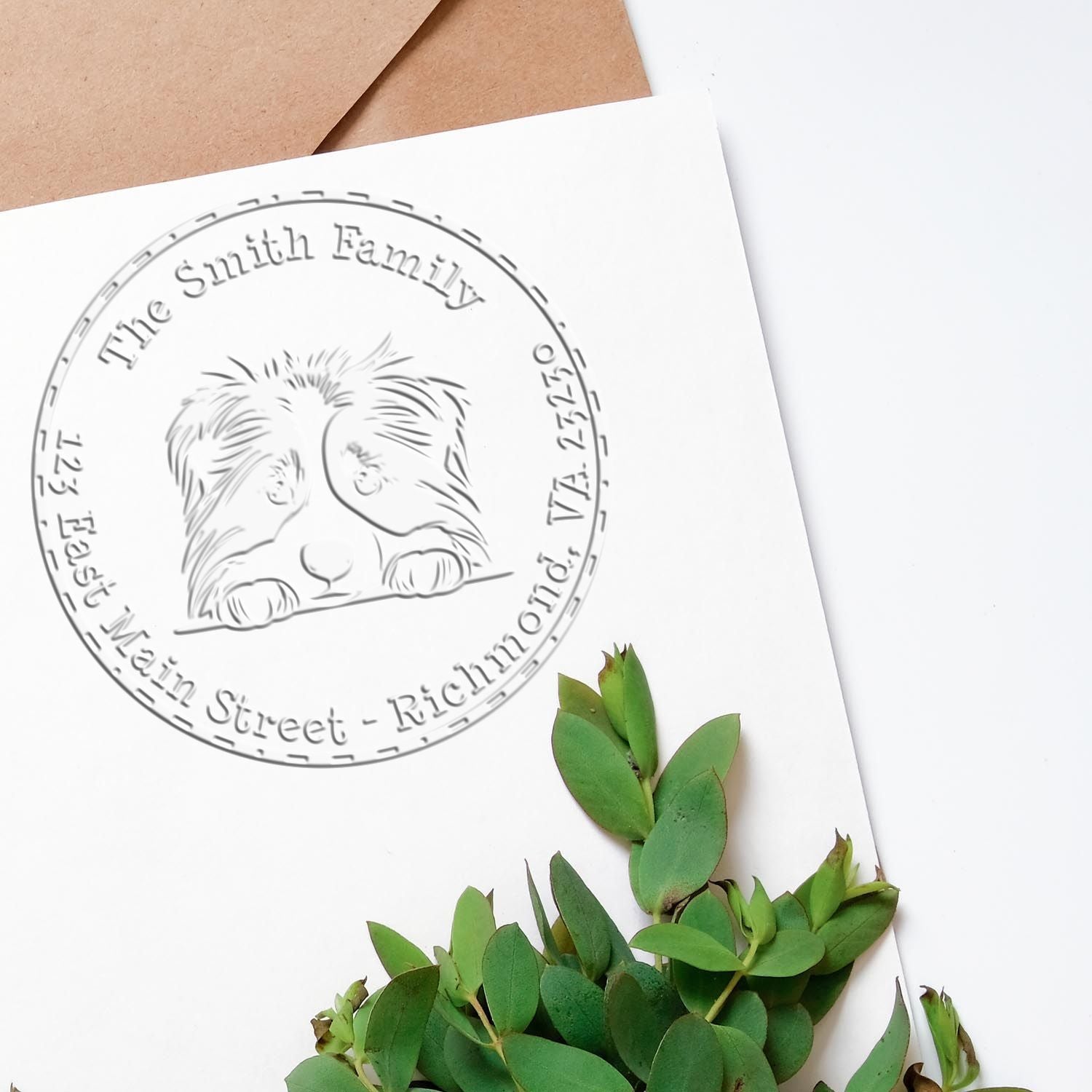 Custom embossed circular stamp seal with dog logo on white card, beside green leaves and tan envelopes