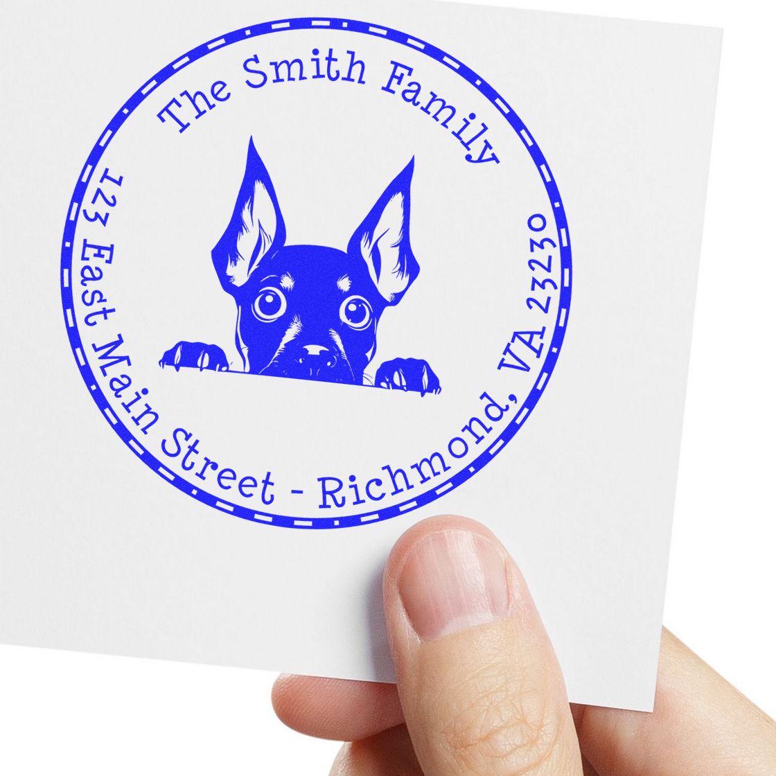 Blue custom address stamp seal with a dog peeking over a line, reading The Smith Family, on white paper.