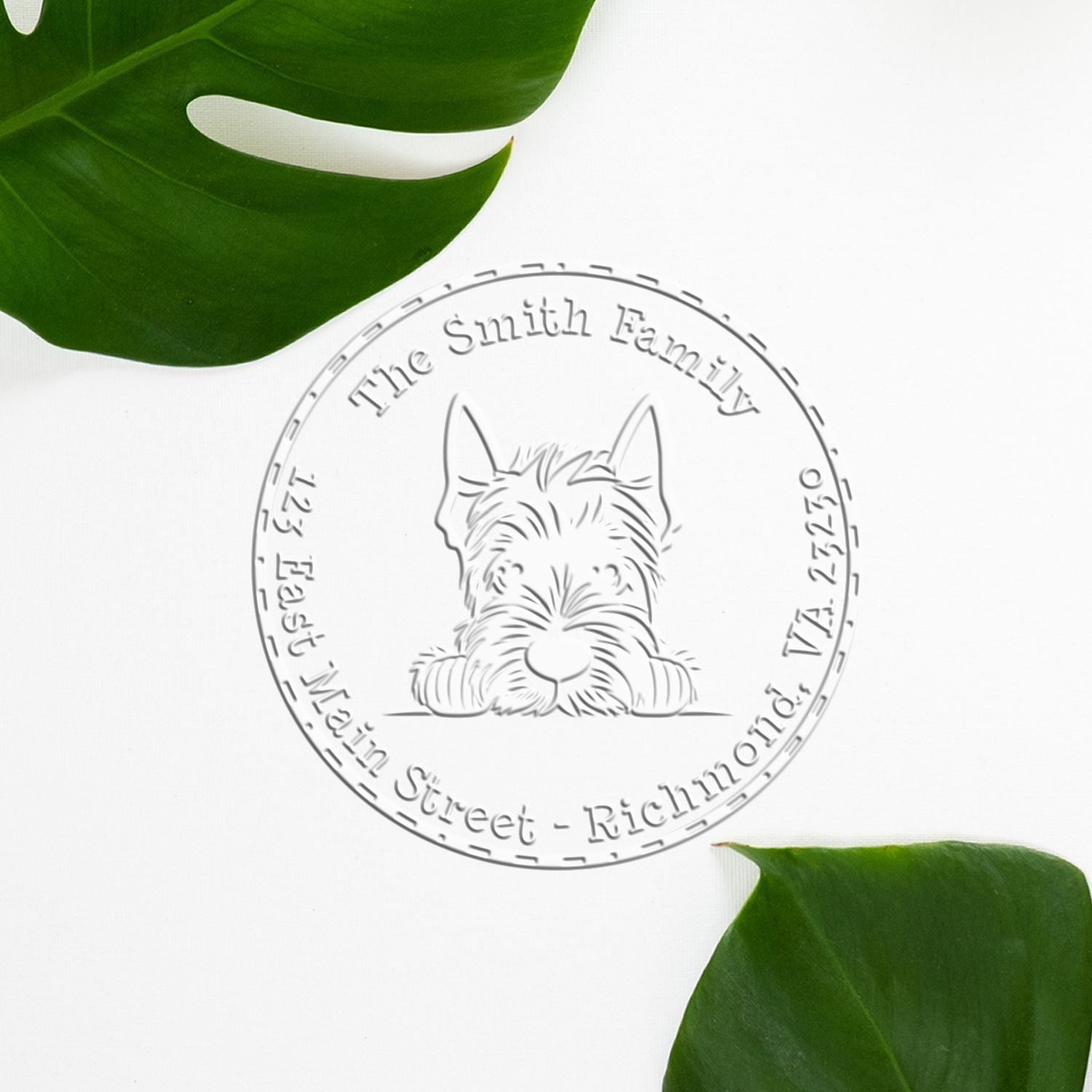 Embossed silver family stamp seal with a dog illustration and circular text, framed by green leaves on white.