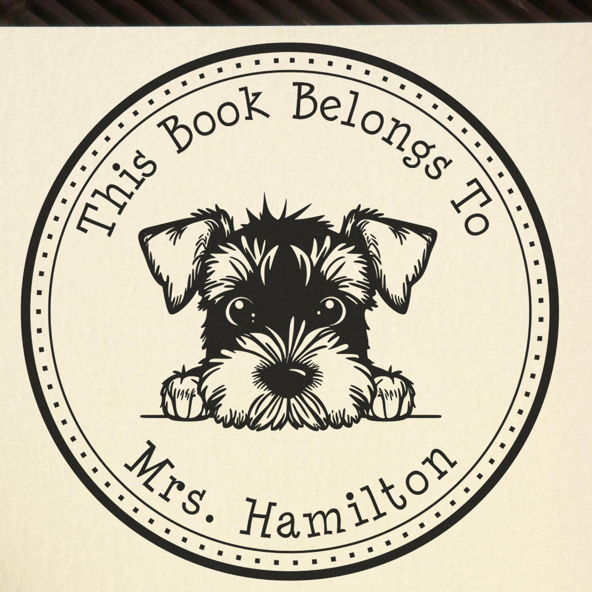 Black circular book stamp seal with schnauzer and cream background, reading This Book Belongs To Mrs. Hamilton.