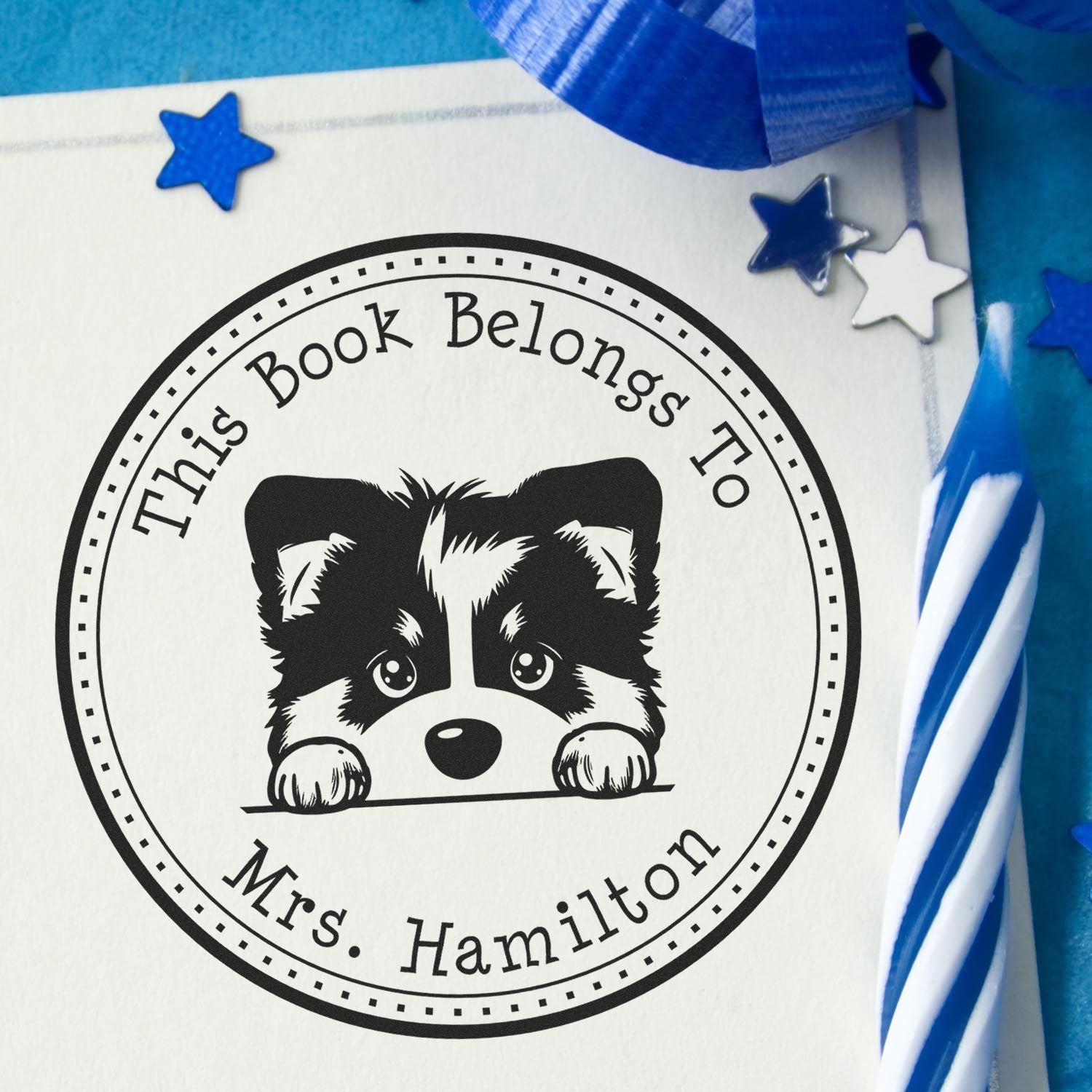 Black round custom book-belongs-to stamp seal with raccoon and Mrs. Hamilton text, accented by blue stars and ribbon.