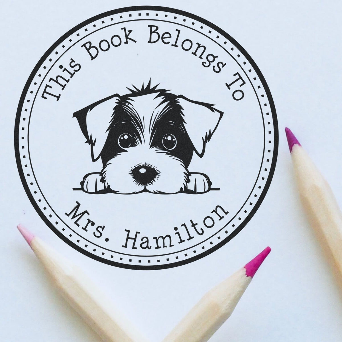 Black circular book-belongs-to-Mrs. Hamilton stamp seal with puppy graphic, surrounded by pink-tipped pencils.