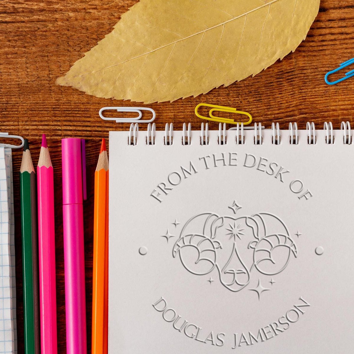 Shiny Aries Ram astrological stamp with sun and stars design, showing the embossed seal in use on paper.